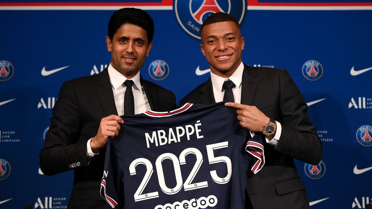 Paris Saint-Germain's CEO Nasser Al-Khelaifi (L) and French forward Kylian Mbappe (R) pose with a jersey at the end of a press conference at the Parc des Princes stadium in Paris on May 23, 2022, two days after the club won the Ligue 1 title for a record-equalling tenth time and its superstar striker Mbappe chose to sign a new contract until 2025 at PSG rather than join Real Madrid.