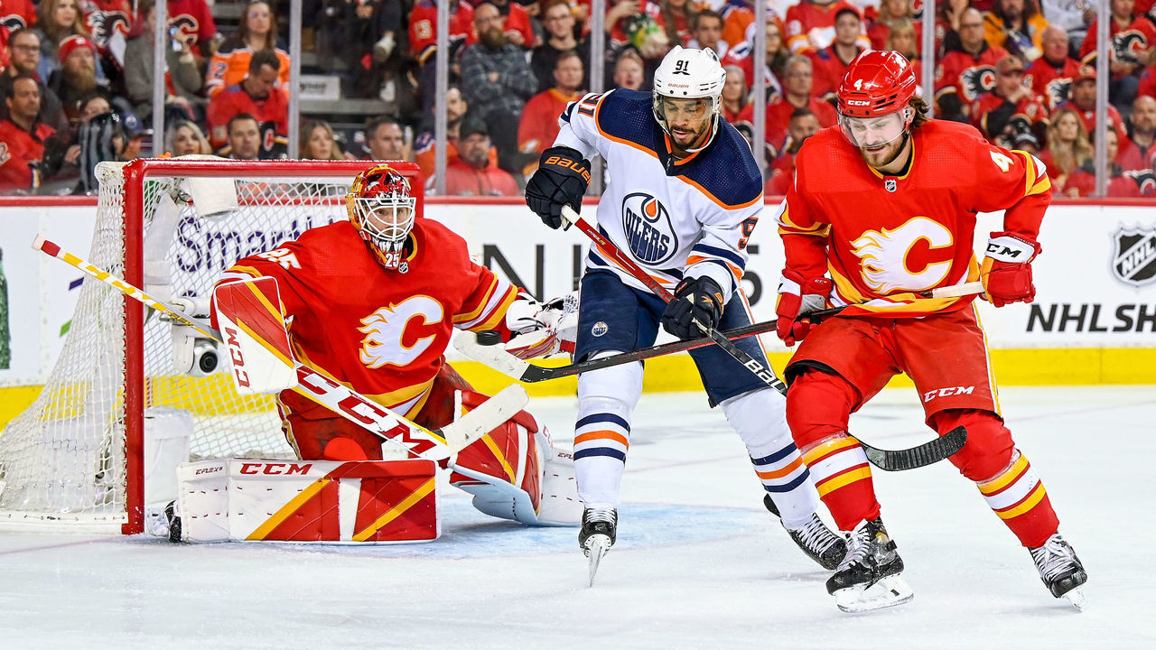 CALGARY, AB - MAY 20: Calgary Flames Goalie Jacob Markstrom (25) makes a save as Edmonton Oilers Left Wing Evander Kane (91) and Calgary Flames Defenceman Rasmus Andersson (4) compete for position during the third period of game 2 of the second round of the NHL Stanley Cup Playoffs between the Calgary Flames and the Edmonton Oilers on May 20, 2022, at the Scotiabank Saddledome in Calgary, AB.