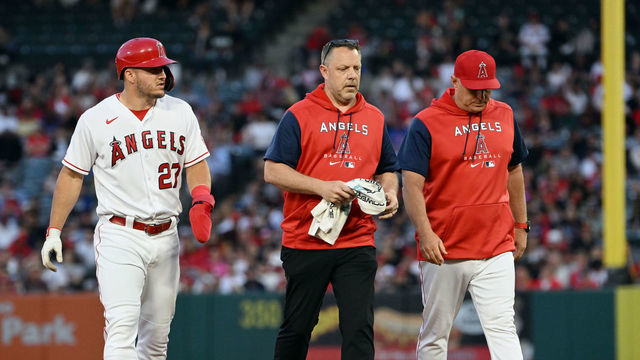ANAHEIM, CA - JUNE 07: Los Angeles Angels centerfielder Mike Trout (27) walks off the field and heads for the dugout with trainer Mike Frostad and interim manager Phil Nevin (88) after hitting a double in the third inning of an MLB baseball game against the Boston Red Sox played on June 7, 2022 at Angel Stadium in Anaheim, CA.
