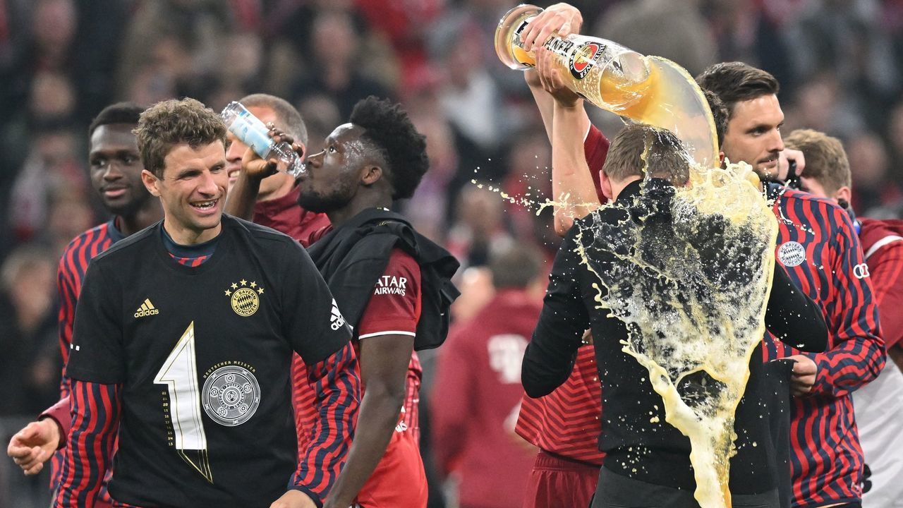 TOPSHOT - Bayern Munich's German head coach Julian Nagelsmann (R) is soaked with beer as they celebrate after the German first division Bundesliga football match FC Bayern Munich v BVB Borussia Dortmund in Munich, southern Germany on April 23, 2022. - Bayern Munich were crowned Bundesliga champions for the 10th consecutive season on April 23, 2022 after a 3-1 home win over Borussia Dortmund in the top-of-the-table showdown. - DFL REGULATIONS PROHIBIT ANY USE OF PHOTOGRAPHS AS IMAGE SEQUENCES AND/OR QUASI-VIDEO