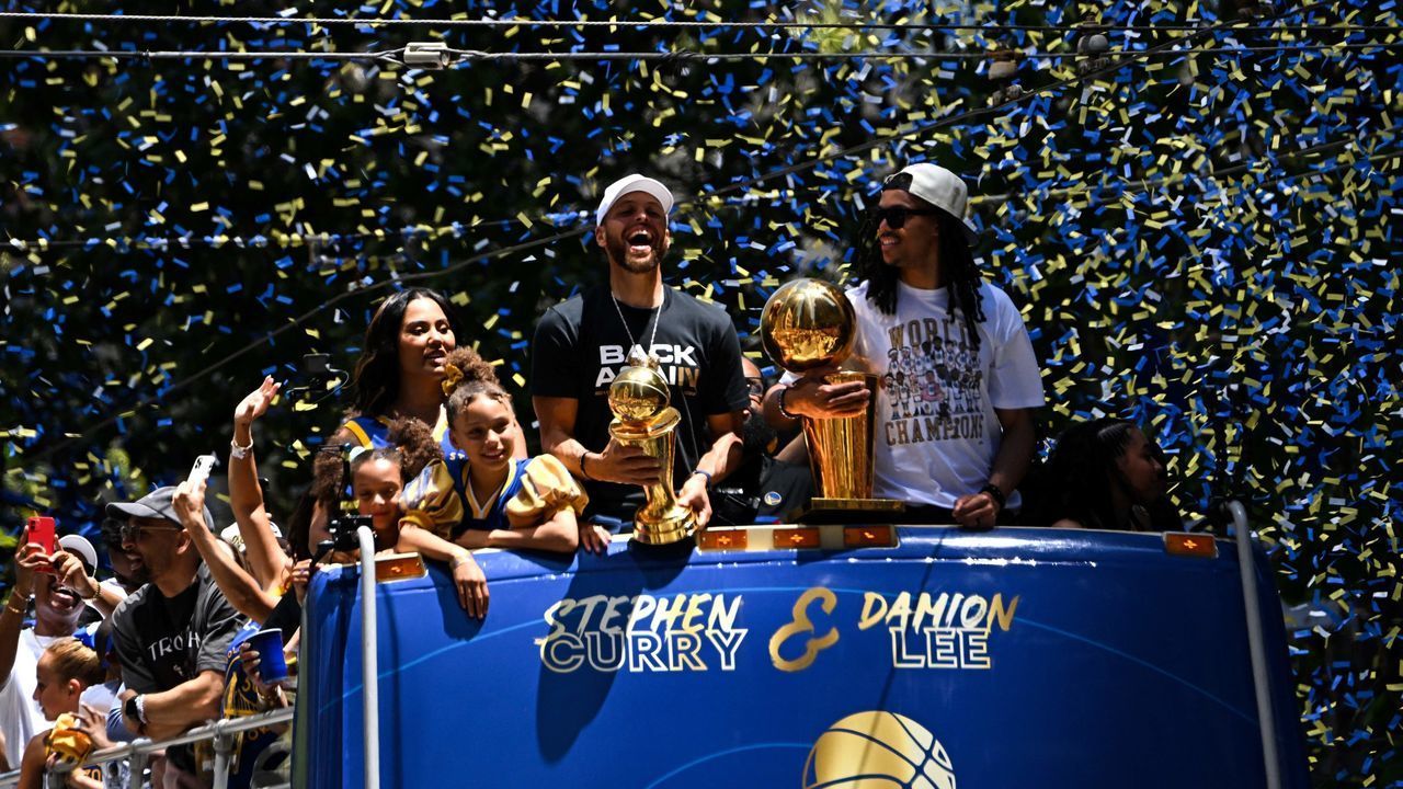 US basketball player Stephen Curry (L) holds the MVP trophy alongside teammate Damion Lee (R) as they celebrate from a double decker bus during the Golden State Warriors NBA Championship victory parade along Market Street in San Francisco, California on June 20, 2022.