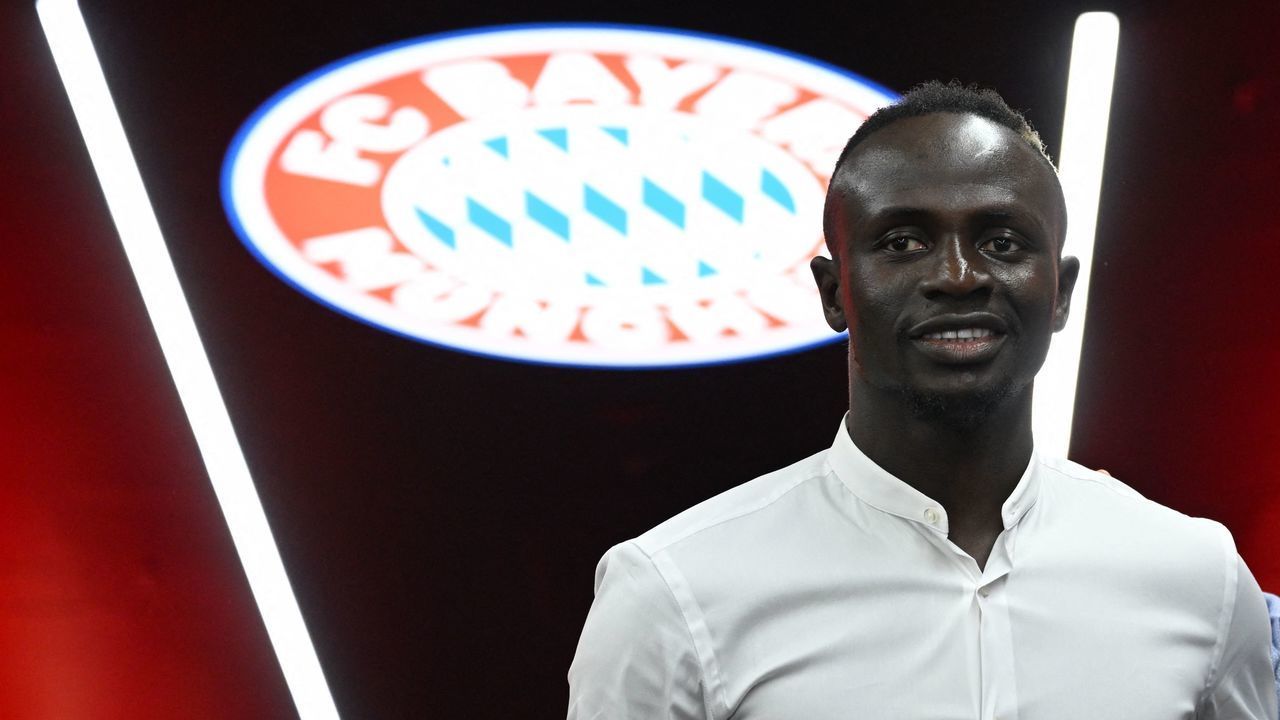 Bayern Munich's Senegalese new forward Sadio Mane poses in front of the Bayern Munich logo during a press conference after he signed a three-year deal with German first division football club FC Bayern Munich, in Munich, southern Germany, on June 22, 2022. - Bayern Munich confirmed the signing of Sadio Mane from Liverpool on June 22, as the Senegal forward signed a three-year deal with the Bundesliga champions. Bayern have reportedly paid a fee which could rise to 41 million euros (USD 43 million) for Mane.