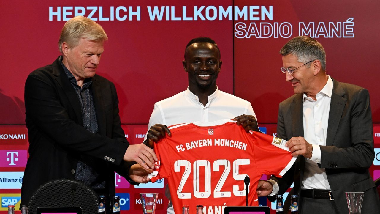 Bayern Munich's Senegalese new forward Sadio Mane (C) with his jersey poses next to Bayern Munich CEO Oliver Kahn (L) and President Herbert Hainer during a press conference after he signed a three-year deal with German first division football club FC Bayern Munich, in Munich, southern Germany, on June 22, 2022. - Bayern Munich confirmed the signing of Sadio Mane from Liverpool on June 22, as the Senegal forward signed a three-year deal with the Bundesliga champions. Bayern have reportedly paid a fee which could rise to 41 million euros (USD 43 million) for Mane.