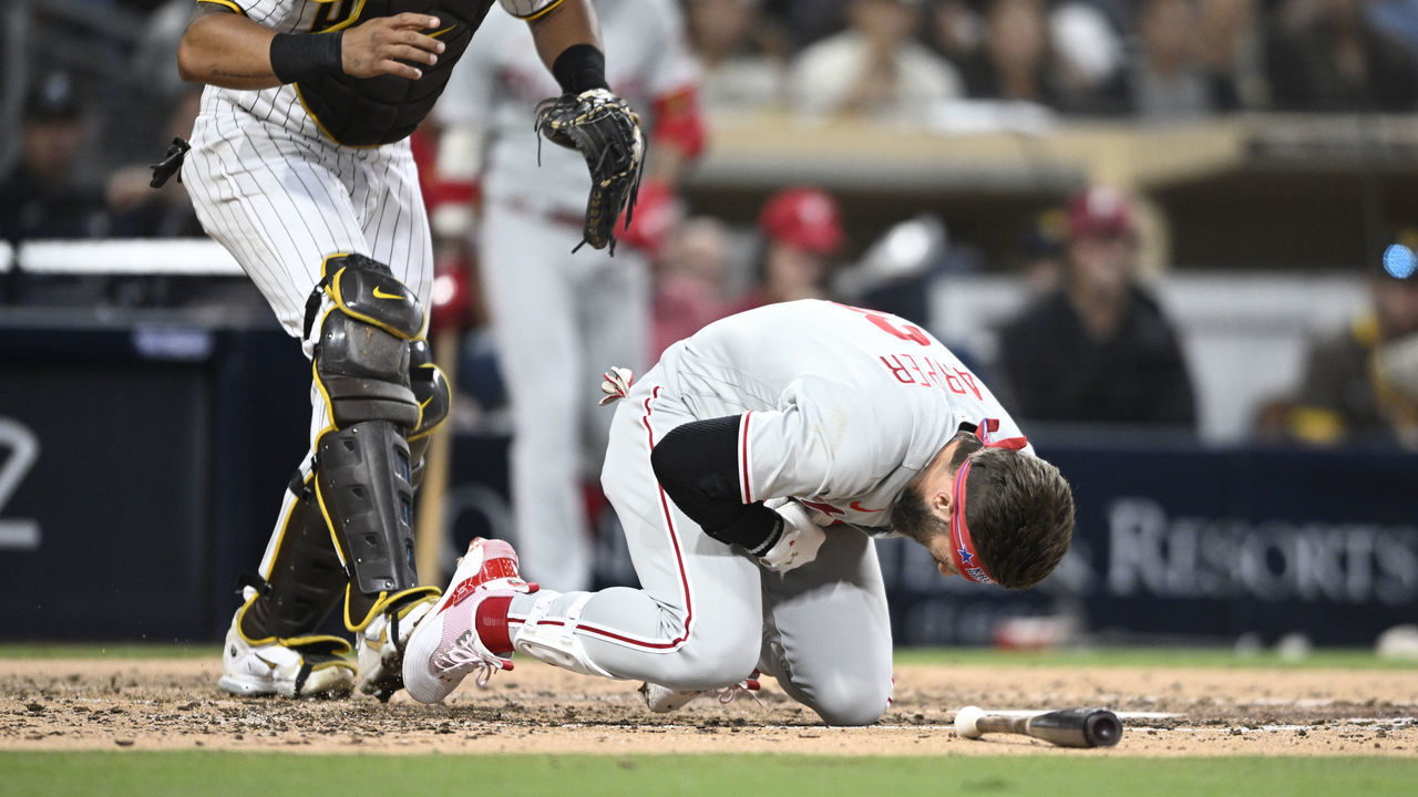 SAN DIEGO, CA - JUNE 25: Bryce Harper #3 of the Philadelphia Phillies falls after being hit with a pitch as Jorge Alfaro #38 of the San Diego Padres looks on during the fourth inning of a baseball game June 25, 2022 at Petco Park in San Diego, California.
