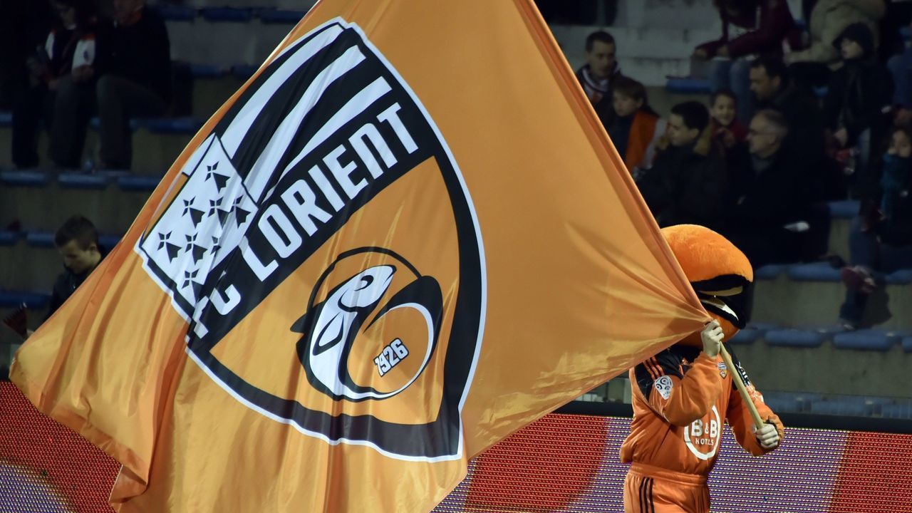A man walks along the ground with a flag of the Lorient football team to cheer the players before the French L1 football match between FC Lorient and Stade Rennais FC on April 4, 2015 at the Stade du Moustoir in Lorient. AFP PHOTO GEORGES GOBET
