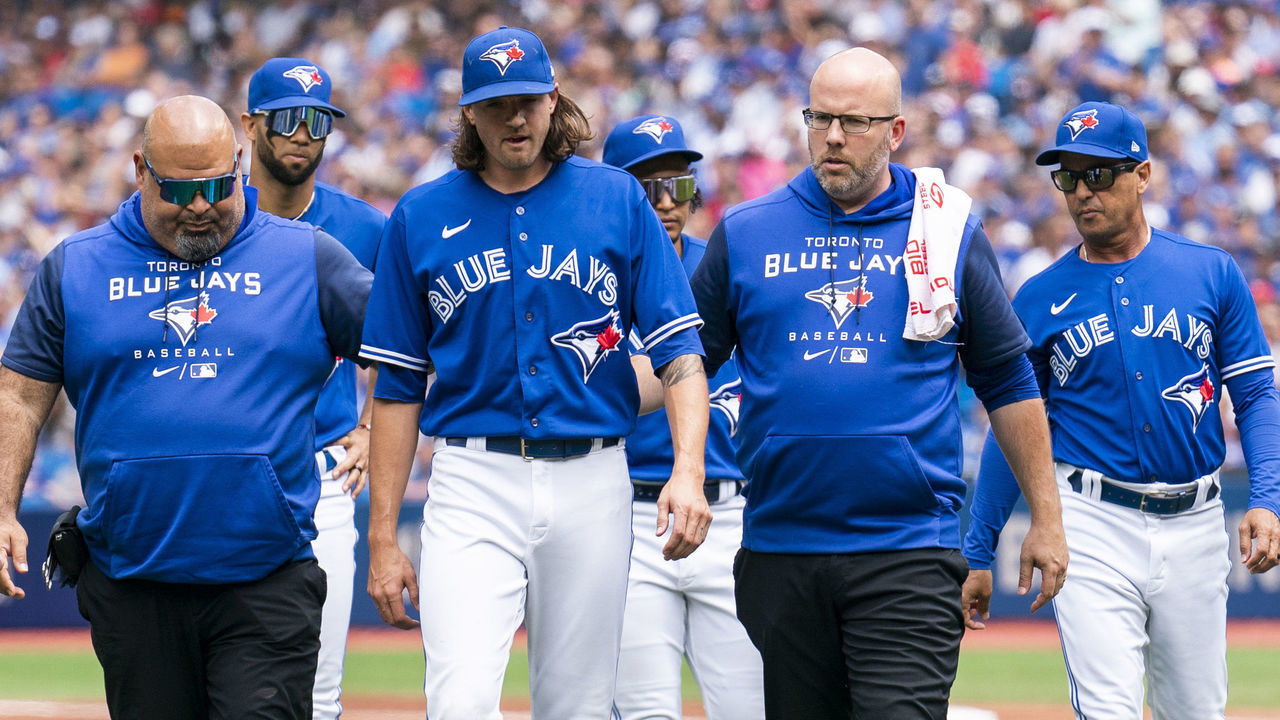 TORONTO, ON - JULY 2: Kevin Gausman #34 of the Toronto Blue Jays is brought off the field with trainers and players after being hit by a ball against the Tampa Bay Rays in the second inning during game one of a doubleheader at the Rogers Centre on July 2, 2022 in Toronto, Ontario, Canada.