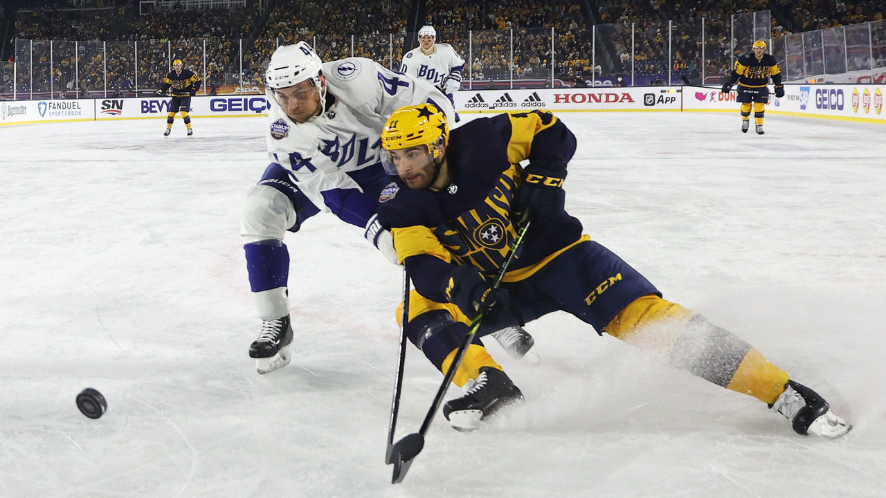 NASHVILLE, TENNESSEE - FEBRUARY 26: Luke Kunin #11 of the Nashville Predators and Jan Rutta #44 of the Tampa Bay Lightning skate for the puck in the third period during the 2022 Navy Federal Credit Union NHL Stadium Series between the Tampa Bay Lightning and the Nashville Predators at Nissan Stadium on February 26, 2022 in Nashville, Tennessee.