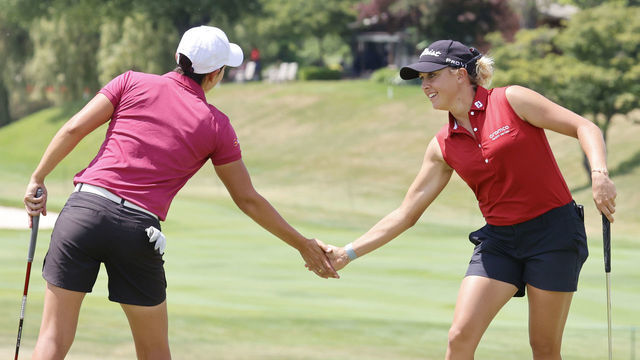 MIDLAND, MI - JULY 14: LPGA player Dewi Weber in pink top give a fist bump to teammate Pauline Roussin-Bouchard in red top after Pauline made a birdie putt on the 15th hole on July 14, 2022, during the Dow Great Lakes Bay Invitational at Midland Country Club in Midland, Michigan.