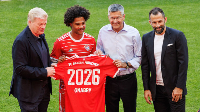 16 July 2022, Bavaria, Munich: Soccer: Bundesliga, team presentation and training FC Bayern Munich at the Allianz Arena: Oliver Kahn, member of the board of FC Bayern (l-r), Serge Gnabry of FC Bayern Munich, Herbert Hainer, club president of FC Bayern, and Hasan Salihamidzic, sports director of FC Bayern, stand on the pitch holding a jersey with the year 2026. Gnabry has prematurely extended his contract with FC Bayern Munich on a long-term basis until June 30, 2026. Photo: Matthias Balk/dpa