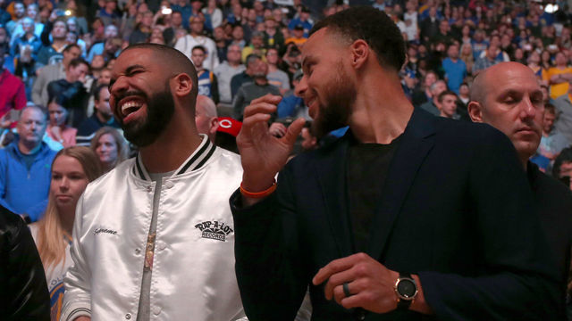 Singer Drake, center, and Golden State Warriors' Stephen Curry, in street clothes, share a moment before the NBA game against the New Orleans Pelicans at Oracle Arena in Oakland, Calif., on Saturday, April 8, 2017. (Ray Chavez/Bay Area News Group)