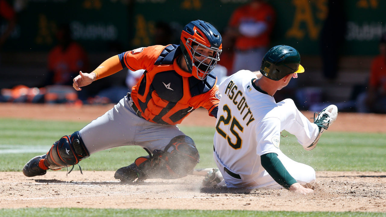 OAKLAND, CALIFORNIA - JULY 27: Stephen Piscotty #25 of the Oakland Athletics slides in safe at home plate ahead of the tag by catcher Korey Lee #38 of the Houston Astros to score on a single by Skye Bolt #11 of the Oakland Athletics in the bottom of the seventh inning at RingCentral Coliseum on July 27, 2022 in Oakland, California.