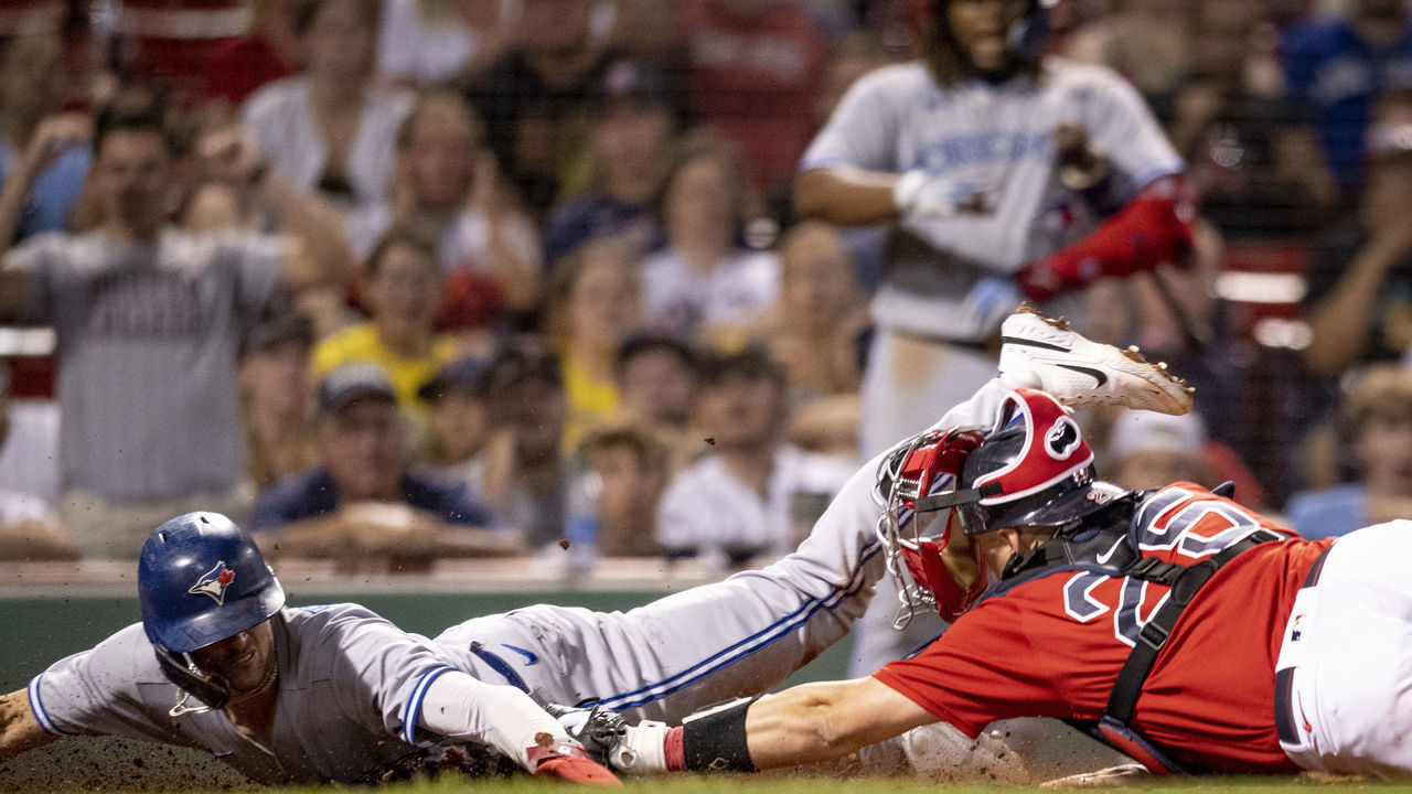 BOSTON, MA - AUGUST 25: Cavan Biggio #8 of the Toronto Blue Jays slides to score the go-ahead run during the tenth inning of a game against the Boston Red Sox on August 25, 2022 at Fenway Park in Boston, Massachusetts.