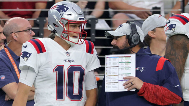 LAS VEGAS, NEVADA - AUGUST 26: Quarterback Mac Jones #10 and senior football advisor Matt Patricia of the New England Patriots talk on a sideline during their preseason game against the Las Vegas Raiders at Allegiant Stadium on August 26, 2022 in Las Vegas, Nevada. The Raiders defeated the Patriots 23-6.