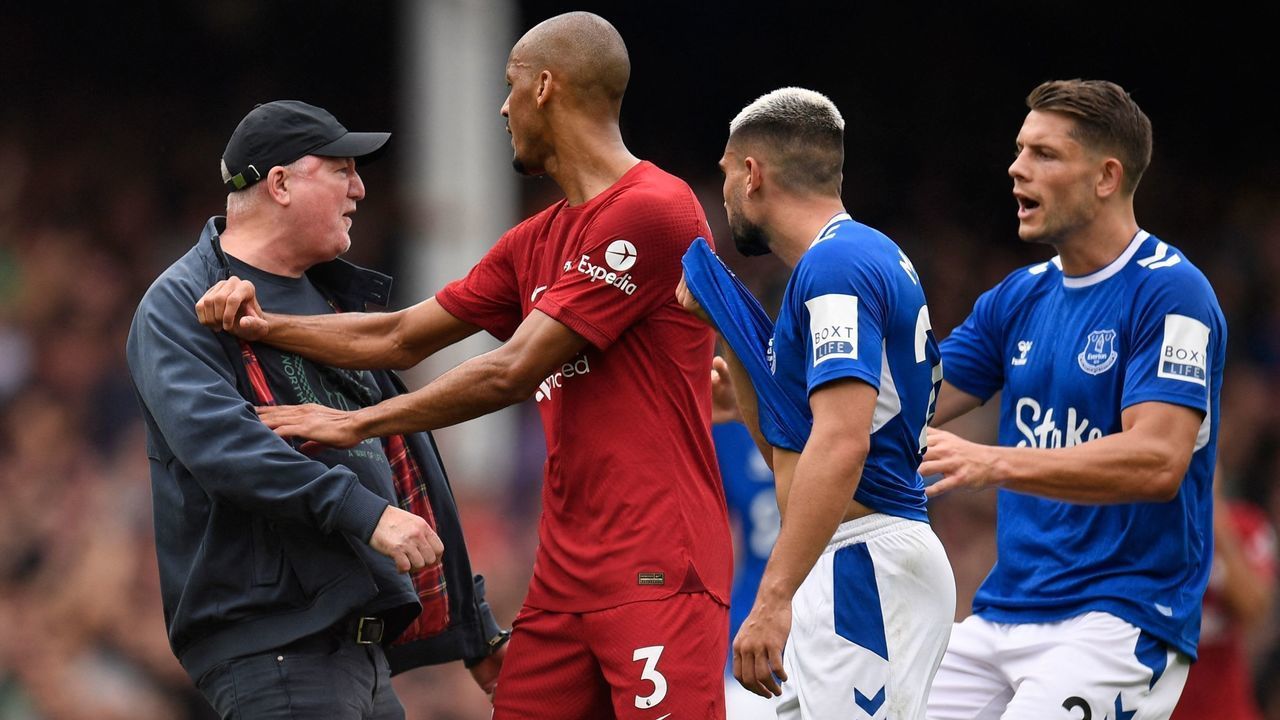 A pitch invader is restained by players during the English Premier League football match between Everton and Liverpool at Goodison Park in Liverpool, north west England on September 3, 2022. - RESTRICTED TO EDITORIAL USE. No use with unauthorized audio, video, data, fixture lists, club/league logos or 'live' services. Online in-match use limited to 120 images. An additional 40 images may be used in extra time. No video emulation. Social media in-match use limited to 120 images. An additional 40 images may be used in extra time. No use in betting publications, games or single club/league/player publications.