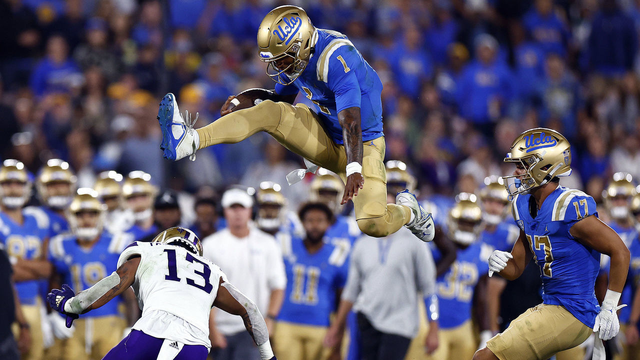 PASADENA, CALIFORNIA - SEPTEMBER 30: Dorian Thompson-Robinson #1 of the UCLA Bruins jumps over Kamren Fabiculanan #13 of the Washington Huskies in the second quarter at Rose Bowl Stadium on September 30, 2022 in Pasadena, California.