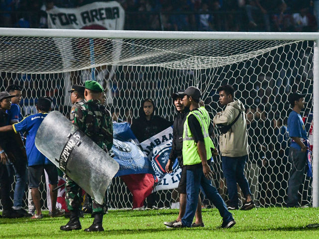 This picture taken on October 1, 2022 shows Indonesian army and police securing the pitch after a football match between Arema FC and Persebaya Surabaya at Kanjuruhan stadium in Malang, East Java. - At least 127 people died at a football stadium in Indonesia late on October 1 when fans invaded the pitch and police responded with tear gas, triggering a stampede, officials said.