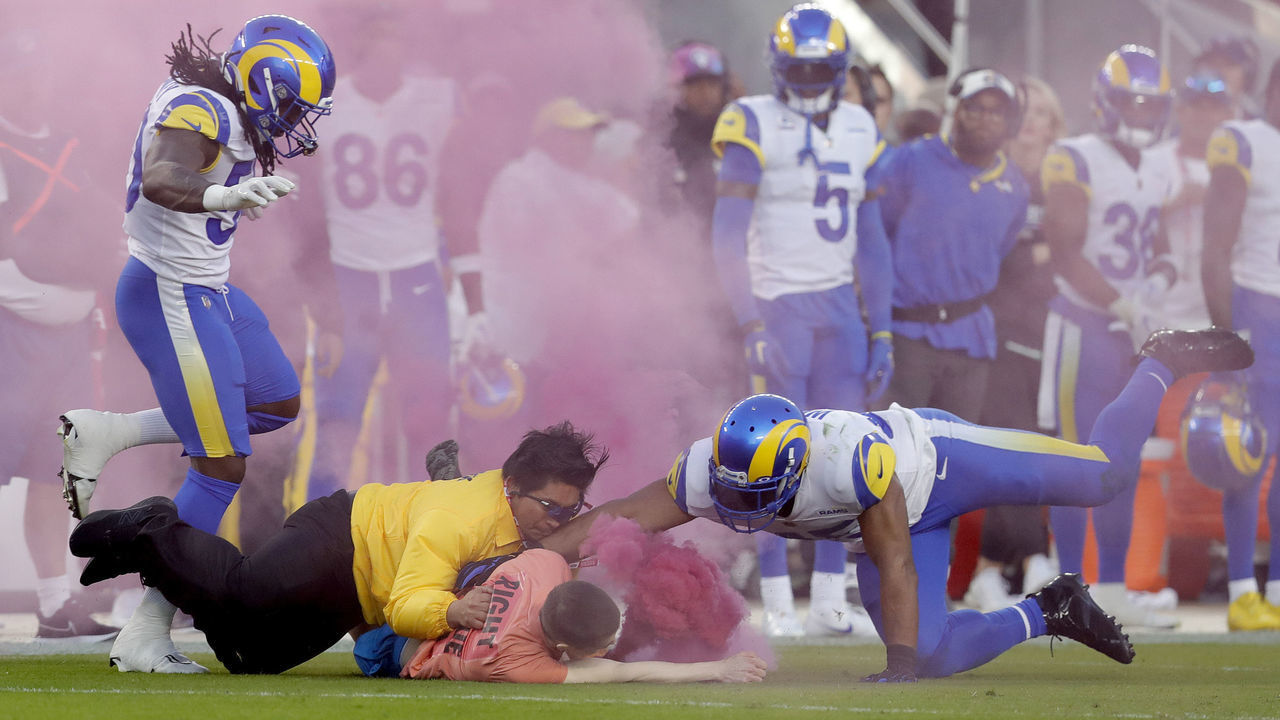 SANTA CLARA, CALIFORNIA - OCTOBER 03: A protester with a smoke bomb is tackled on the field by Los Angeles Rams' Bobby Wagner, #45 Takkarist McKinley #50 and a security guard during their NFL game against the San Francisco 49ers at Levis Stadium in Santa Clara, Calif., on Monday, Oct. 3, 2022. (Jane Tyska/Digital First Media/East Bay Times via Getty Images)
