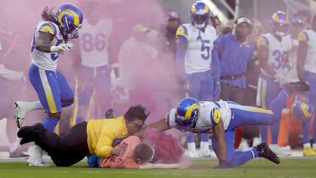 SANTA CLARA, CALIFORNIA - OCTOBER 03: A protester with a smoke bomb is tackled on the field by Los Angeles Rams' Bobby Wagner, #45 Takkarist McKinley #50 and a security guard during their NFL game against the San Francisco 49ers at Levis Stadium in Santa Clara, Calif., on Monday, Oct. 3, 2022. (Jane Tyska/Digital First Media/East Bay Times via Getty Images)