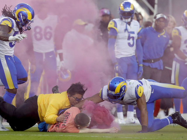 SANTA CLARA, CALIFORNIA - OCTOBER 03: A protester with a smoke bomb is tackled on the field by Los Angeles Rams' Bobby Wagner, #45 Takkarist McKinley #50 and a security guard during their NFL game against the San Francisco 49ers at Levis Stadium in Santa Clara, Calif., on Monday, Oct. 3, 2022. (Jane Tyska/Digital First Media/East Bay Times via Getty Images)