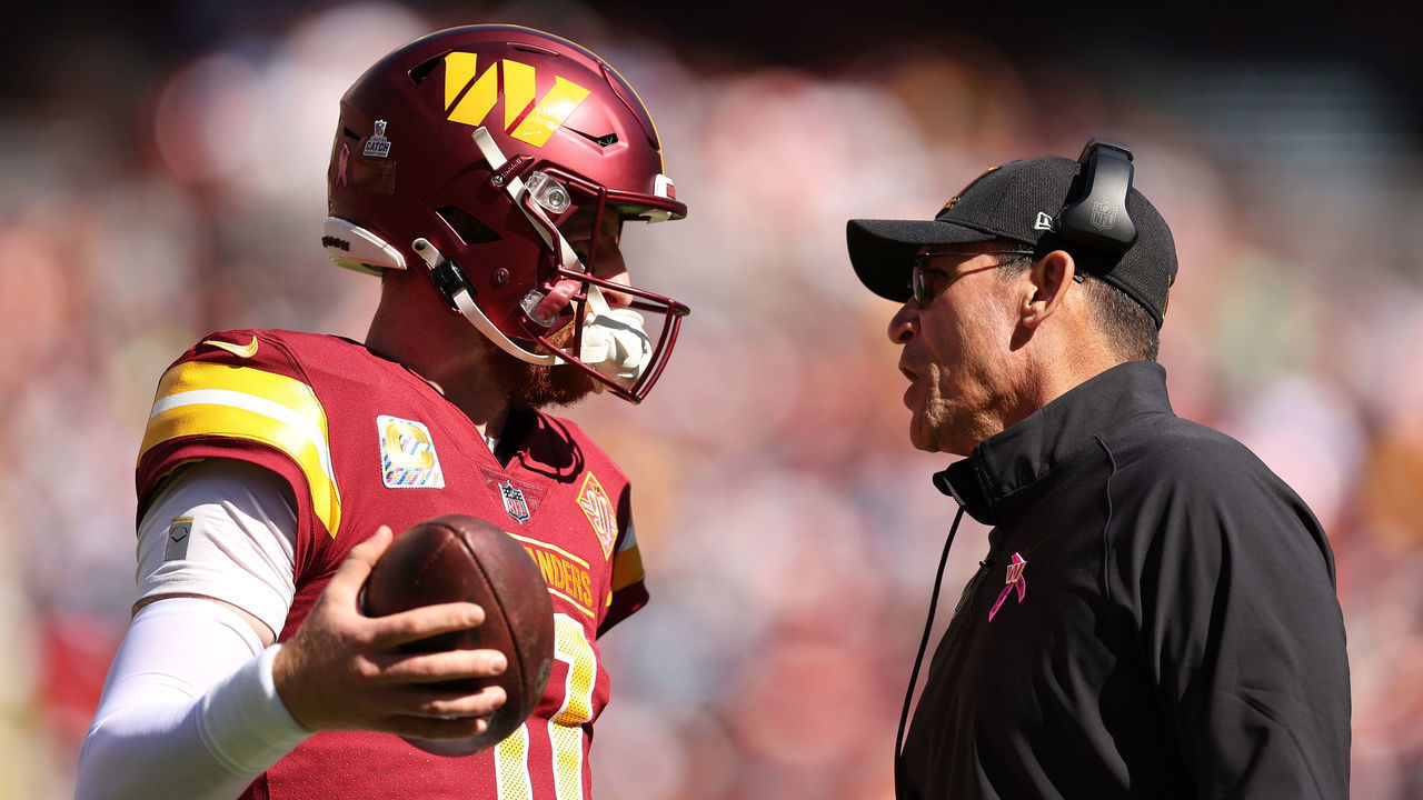 LANDOVER, MARYLAND - OCTOBER 09: Carson Wentz #11 of the Washington Commanders talks with head coach Ron Rivera during the first half against the Tennessee Titans at FedExField on October 09, 2022 in Landover, Maryland.