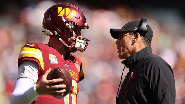 LANDOVER, MARYLAND - OCTOBER 09: Carson Wentz #11 of the Washington Commanders talks with head coach Ron Rivera during the first half against the Tennessee Titans at FedExField on October 09, 2022 in Landover, Maryland.
