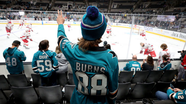 SAN JOSE, CALIFORNIA - OCTOBER 14: A fan watches Brent Burns #8 of the Carolina Hurricanes warm up before their game against the San Jose Sharks at SAP Center on October 14, 2022 in San Jose, California. Burns played for the Sharks for 11 seasons and is the franchise's all-time leader in goals, assists, and points.