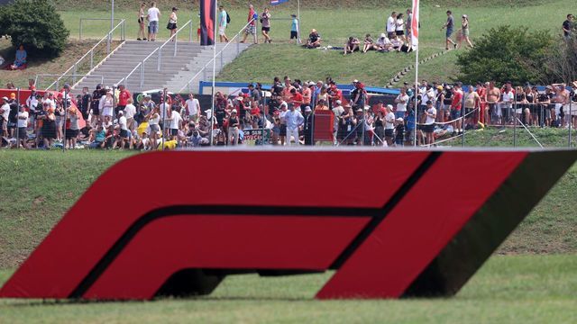 Spectators are seen behind a large Formula One F1 logo ahead of the Formula One Hungarian Grand Prix at the Hungaroring race track in Mogyorod near Budapest on August 1, 2021.