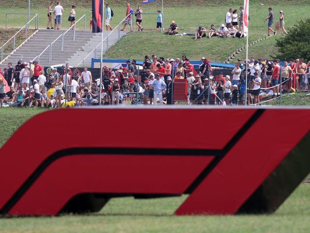 Spectators are seen behind a large Formula One F1 logo ahead of the Formula One Hungarian Grand Prix at the Hungaroring race track in Mogyorod near Budapest on August 1, 2021.