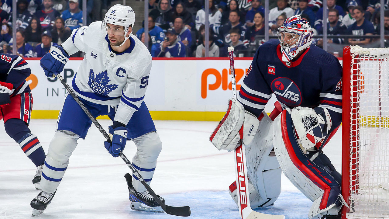 WINNIPEG, CANADA - OCTOBER 22: John Tavares #91 of the Toronto Maple Leafs and goaltender Connor Hellebuyck #37 of the Winnipeg Jets keep an eye on the play during first period action at the Canada Life Centre on October 22, 2022 in Winnipeg, Manitoba, Canada.