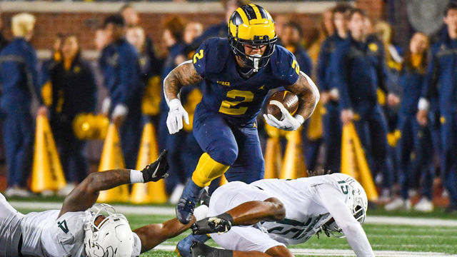 ANN ARBOR, MICHIGAN - OCTOBER 29: Blake Corum #2 of the Michigan Wolverines runs with the ball while avoiding tackles by Jacoby Windmon #4 and Angelo Grose #15 of the Michigan State Spartans during the first half of a college football game at Michigan Stadium on October 29, 2022 in Ann Arbor, Michigan.