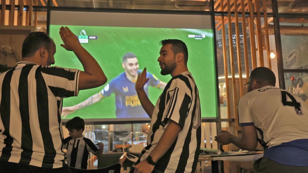 Saudi fans of English football club Newcastle United celebrate a goal scored against Tottenham during as they watch the match at a cafe, in Riyadh on October 23, 2022. - The Saudi purchase of Newcastle - its sovereign wealth fund paid $408 million for an 80 percent stake - has proved deeply controversial, with critics quick to deride it as an example of "sportswashing", or using athletics to distract from human rights abuses.The takeover was rubber-stamped by the Premier League only after it received legally binding assurances the Saudi state would not control the team.