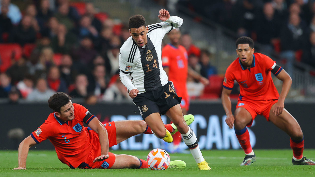 LONDON, ENGLAND - SEPTEMBER 26: Jamal Musiala of Germany runs beyond the challenge of Harry Maguire of England during the UEFA Nations League League A Group 3 match between England and Germany at Wembley Stadium on September 26, 2022 in London, England.
