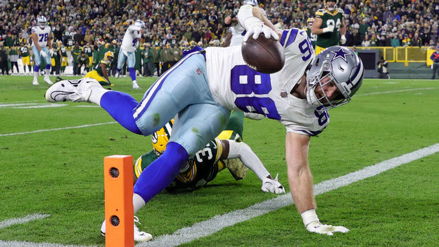 GREEN BAY, WISCONSIN - NOVEMBER 13: Dalton Schultz #86 of the Dallas Cowboys dives past Adrian Amos #31 of the Green Bay Packers while scoring a touchdown during the second quarter at Lambeau Field on November 13, 2022 in Green Bay, Wisconsin.