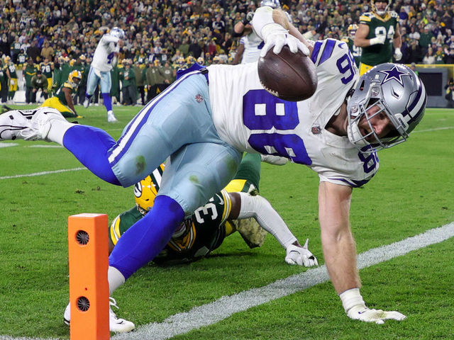 GREEN BAY, WISCONSIN - NOVEMBER 13: Dalton Schultz #86 of the Dallas Cowboys dives past Adrian Amos #31 of the Green Bay Packers while scoring a touchdown during the second quarter at Lambeau Field on November 13, 2022 in Green Bay, Wisconsin.