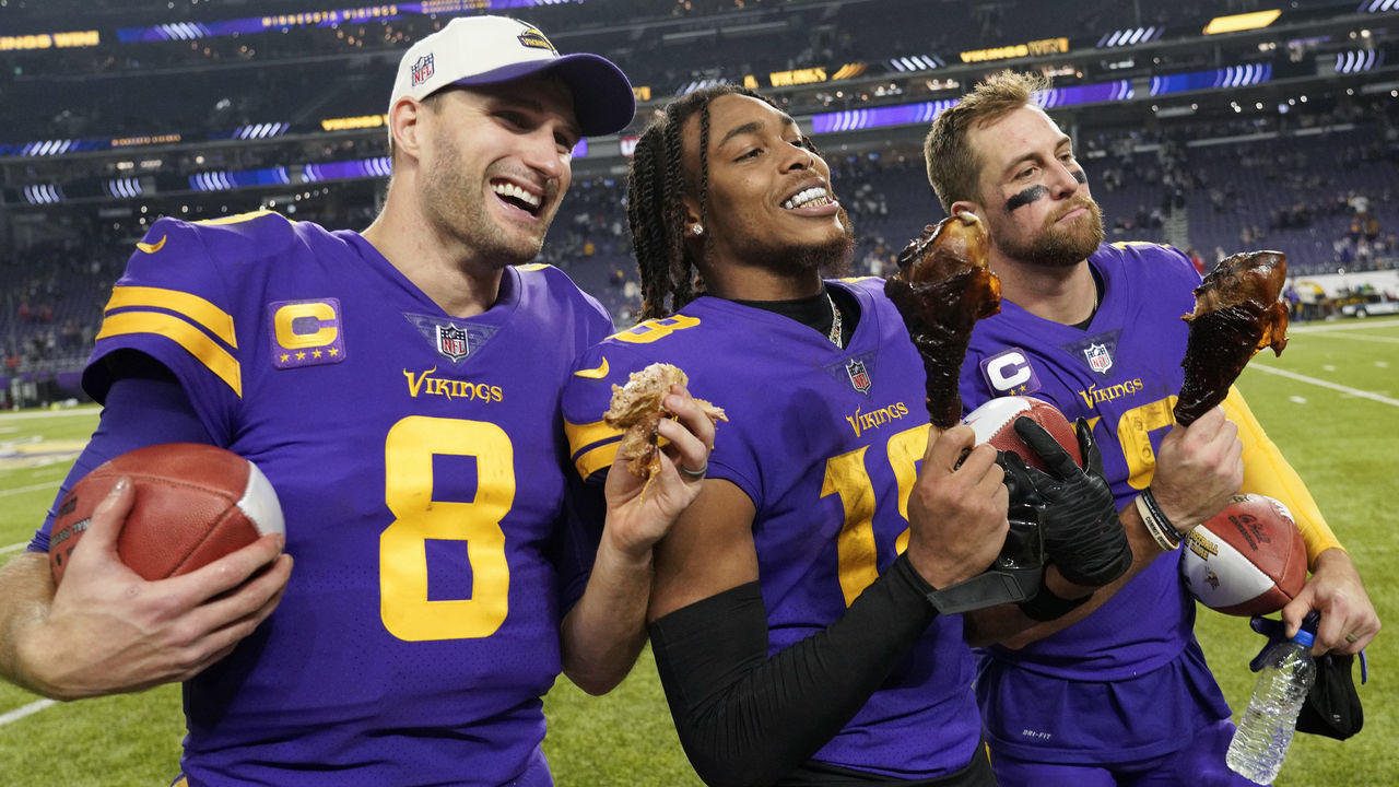 MINNEAPOLIS, MINNESOTA - NOVEMBER 24: Kirk Cousins #8, Justin Jefferson #18 and Adam Thielen #19 of the Minnesota Vikings eat turkey legs on the field after defeating the New England Patriots at U.S. Bank Stadium on November 24, 2022 in Minneapolis, Minnesota.