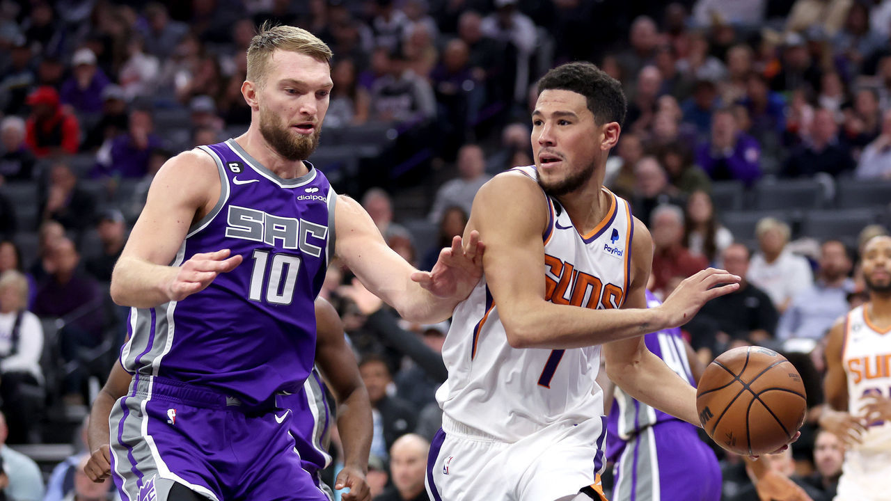 SACRAMENTO, CALIFORNIA - NOVEMBER 28: Devin Booker #1 of the Phoenix Suns is guarded by Domantas Sabonis #10 of the Sacramento Kings at Golden 1 Center on November 28, 2022 in Sacramento, California.