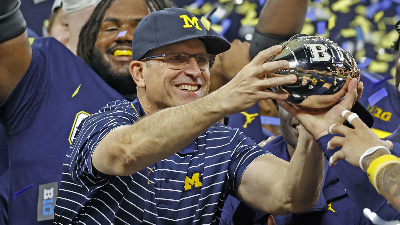 INDIANAPOLIS, IN - DECEMBER 03: Michigan Wolverines coach Jim Harbaugh holds up the trophy after defeating the Purdue Boilermakers on December 3, 2022, and winning the Big 10 Football Championship at Lucas Oil Stadium in Indianapolis, Indiana.