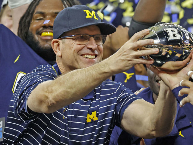INDIANAPOLIS, IN - DECEMBER 03: Michigan Wolverines coach Jim Harbaugh holds up the trophy after defeating the Purdue Boilermakers on December 3, 2022, and winning the Big 10 Football Championship at Lucas Oil Stadium in Indianapolis, Indiana.
