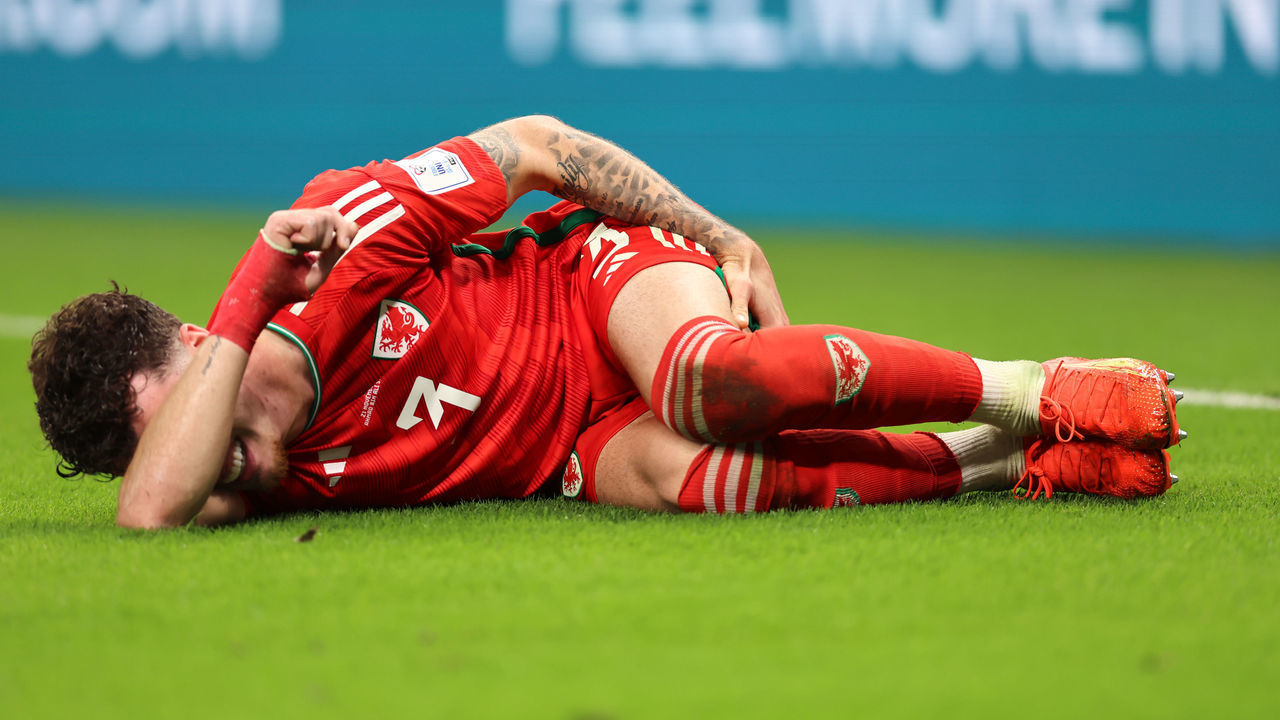 DOHA, QATAR - NOVEMBER 21: Neco Williams of Wales reacts as he lays on the turf grapsing his hamstring during the FIFA World Cup Qatar 2022 Group B match between USA and Wales at Ahmad Bin Ali Stadium on November 21, 2022 in Doha, Qatar.