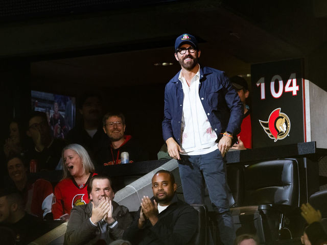 OTTAWA, ON - NOVEMBER 08: Canadian actor Ryan Reynolds stands in the spotlight while being announced during first period National Hockey League action between the Vancouver Canucks and Ottawa Senators on November 8, 2022, at Canadian Tire Centre in Ottawa, ON, Canada.