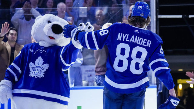 TORONTO, ON - DECEMBER 10: William Nylander #88 of the Toronto Maple Leafs high fives mascot Carlton the Bear after receiving a star of the game after defeating the Calgary Flames at the Scotiabank Arena on December 10, 2022 in Toronto, Ontario, Canada.
