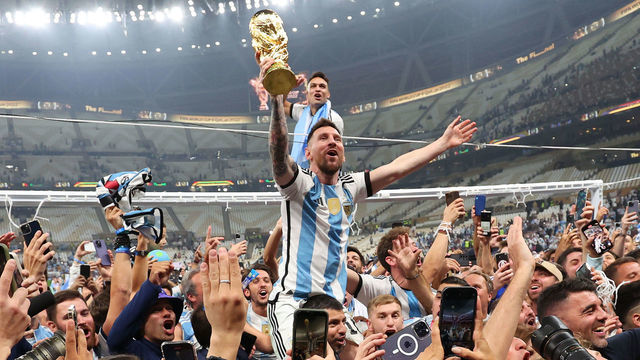 LUSAIL CITY, QATAR - DECEMBER 18: Lionel Messi of Argentina celebrates on Sergio Aguero of Argentina's shoulders with the FIFA World Cup Trophy following his team's victory in during the FIFA World Cup Qatar 2022 Final match between Argentina and France at Lusail Stadium on December 18, 2022 in Lusail City, Qatar.