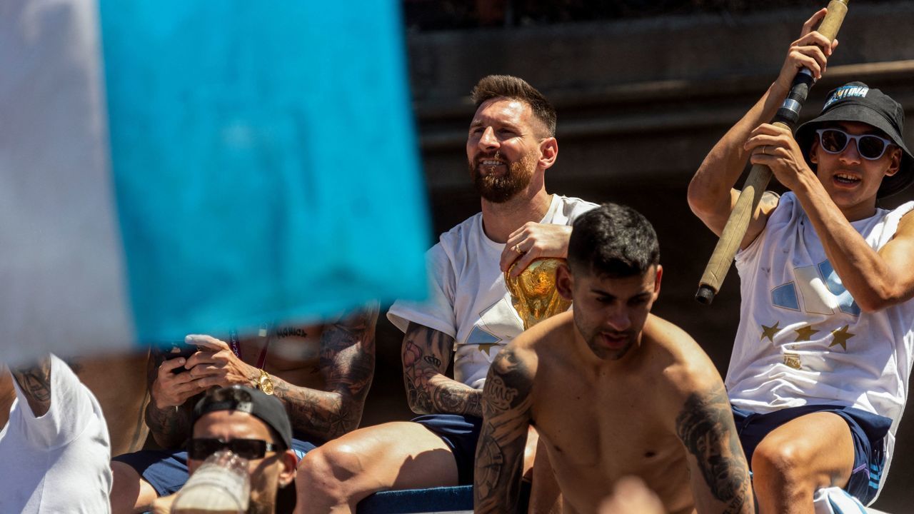 Argentine football star Lionel Messi celebrates on board a bus with a sign reading "World Champions" with supporters after winning the Qatar 2022 World Cup tournament as they tour through Buenos Aires' downtown on December 20, 2022. - Millions of ecstatic fans are expected to cheer on their heroes as Argentina's World Cup winners led by captain Lionel Messi began their open-top bus parade of the capital Buenos Aires on Tuesday following their sensational victory over France.