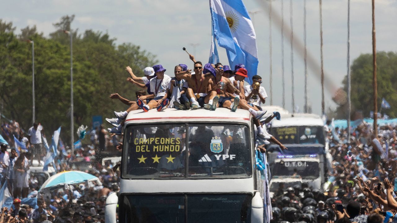 Argentina's players celebrate on board a bus with a sign reading "World Champions" with supporters after winning the Qatar 2022 World Cup tournament as they tour through Buenos Aires' downtown on December 20, 2022. - Millions of ecstatic fans are expected to cheer on their heroes as Argentina's World Cup winners led by captain Lionel Messi began their open-top bus parade of the capital Buenos Aires on Tuesday following their sensational victory over France.