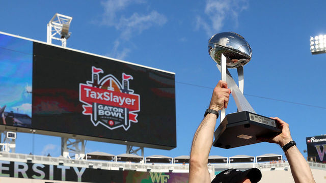 JACKSONVILLE, FLORIDA - DECEMBER 31: Head coach Dave Clawson of the Wake Forest Demon Deacons holds the trophy following a victory against Rutgers Scarlet Knights 38-10 in the TaxSlayer Gator Bowl at TIAA Bank Field on December 31, 2021 in Jacksonville, Florida.