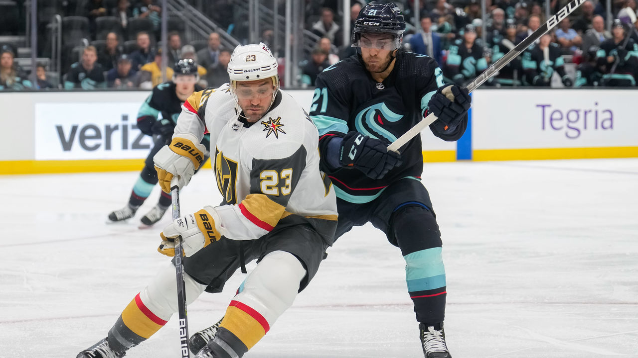 SEATTLE, WASHINGTON - OCTOBER 15: Alec Martinez #23 of the Vegas Golden Knights skates the puck around Alex Wennberg #21 of the Seattle Kraken during the second period of a game at Climate Pledge Arena on October 15, 2022 in Seattle, Washington.