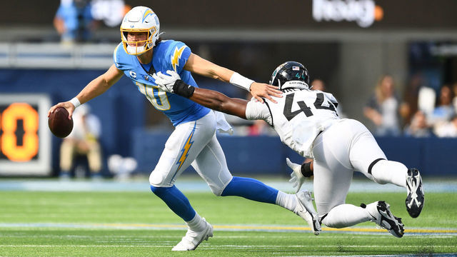 INGLEWOOD, CA - SEPTEMBER 25: Los Angeles Chargers quarterback Justin Herbert (10) eludes the tackle of Jacksonville Jaguars linebacker Travon Walker (44) during the NFL regular season game between the Jacksonville Jaguars and the Los Angeles Chargers on September 25, 2022, at SoFi Stadium in Inglewood, CA.