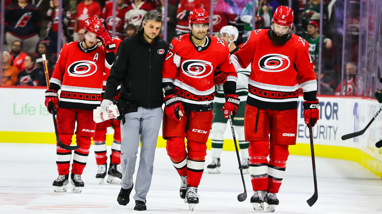 RALEIGH, NC - JANUARY 19: Max Pacioretty #67 of the Carolina Hurricanes is helped off the ice by Brent Burns #8 and head athletic trainer Doug Bennett against the Minnesota Wild during the third period at PNC Arena on January 19, 2023 in Raleigh, North Carolina. The Hurricanes defeated the Wild 5-2.