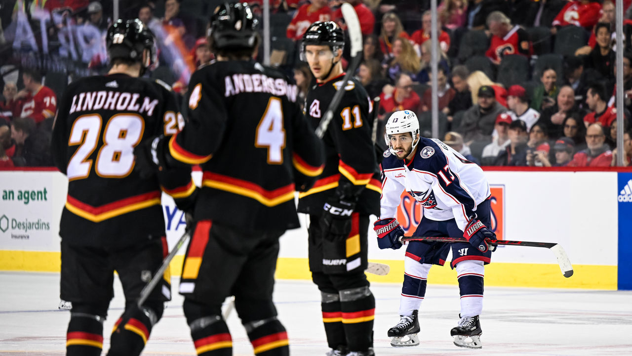 CALGARY, AB - JANUARY 23: Columbus Blue Jackets Left Wing Johnny Gaudreau (13) looks on as Calgary Flames Center Elias Lindholm (28), Calgary Flames Defenceman Rasmus Andersson (4) and Calgary Flames Center Mikael Backlund (11) talk strategy before the start of the overtime period of an NHL game between the Calgary Flames and the Columbus Blue Jackets on January 23, 2023, at the Scotiabank Saddledome in Calgary, AB.