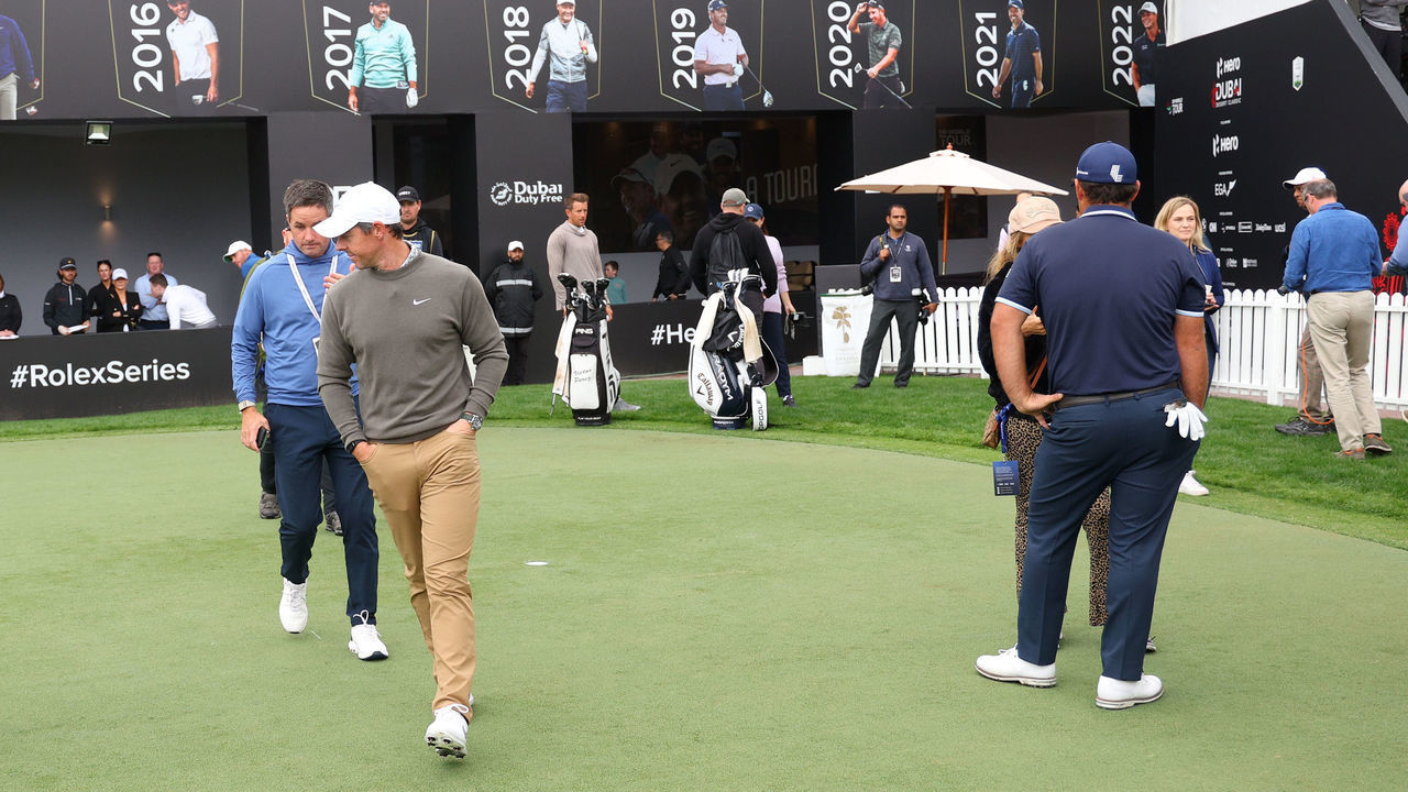 DUBAI, UNITED ARAB EMIRATES - JANUARY 27: Rory McIlroy of Northern Ireland walks past Patrick Reed of The United States on the practice putting green on Day Two the Hero Dubai Desert Classic at Emirates Golf Club on January 27, 2023 in Dubai, United Arab Emirates.